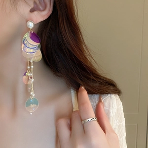 Elegant laser sequin fringe pearl earrings and silver wavy ring worn by a model