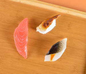 Détail de trois modèles réalistes de sushi au saumon et à l'anguille sur plateau