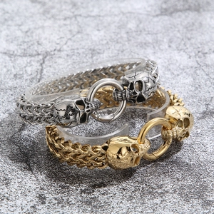 Detail of silver and gold punk skull bracelets with woven metal chain and central ring