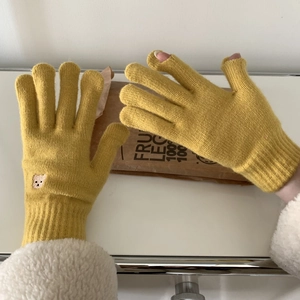 Close-up of yellow knit gloves featuring a cute bear embroidery and touchscreen design