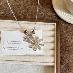 Detail of silver daisy necklace with brown tiger eye beads inside a jewelry box