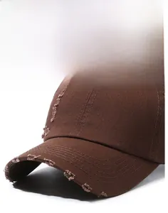 Detail of distressed dark brown baseball cap with hand-worn holes and vintage cotton texture