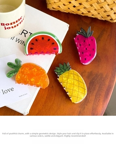 Detailed view of colorful acrylic fruit and vegetable claw clips on a cozy desk