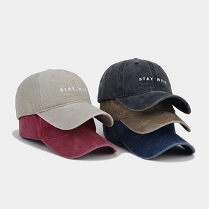 Dettaglio di cappellini in cotone lavato impilati con ricamo STAY WILD in cinque colori