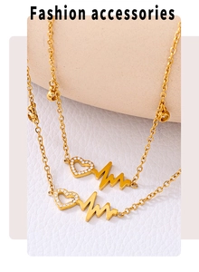 Detailed view of two gold-plated anklets with heartbeat and heart-shaped crystal pendants