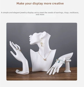 Detailed view of white resin mannequin bust and hand stands for jewelry display on wood