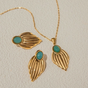 Detailed view of luxury gold steel jewelry set with turquoise fan-shaped pendants