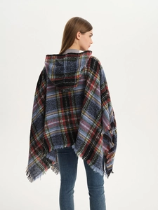 Detail of multi-color plaid hooded poncho with decorative fringe tassels and thick knit fabric