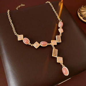 Detail of vintage gold Y-shaped necklace with pink and beige oval gemstones and small diamonds