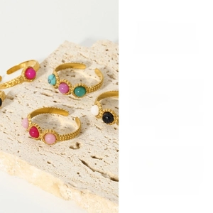 Macro shot of gold adjustable rings with colorful natural stones and wave texture