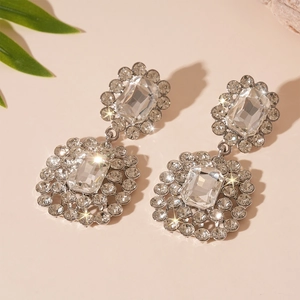 Macro shot of silver crystal flower earrings with rectangular rhinestones on pink background