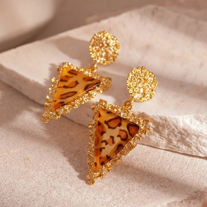 Close-up of golden triangle earrings with leopard print resin inlay and textured finish