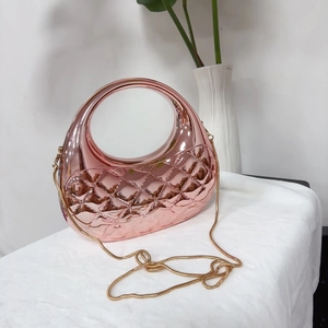 Détail d'une pochette matelassée or rose avec poignée ronde en métal et chaîne serpent