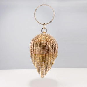 Detail of spherical warm gold evening clutch with rhinestones and tassel decoration