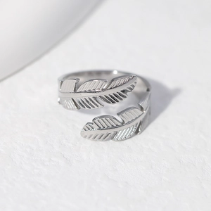 Detailed close-up of adjustable silver feather ring featuring intricate metallic textures