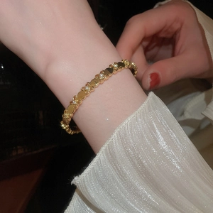 Detail of 18k gold plated fleur-de-lis bracelet with sparkling zircon on a wrist