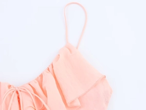 Close-up of adjustable lace-up neckline and tiered ruffles on a light orange midi dress