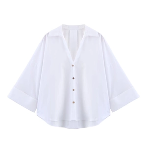 Detail of white poplin shirt featuring a V-neckline and wide folded cuffs in a flat lay view