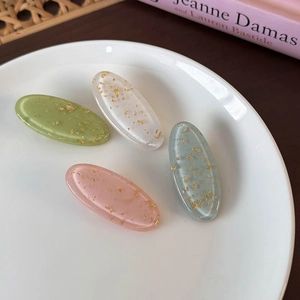 Detail of colorful oval hair clips with gold foil in green, pink, blue, and white colors
