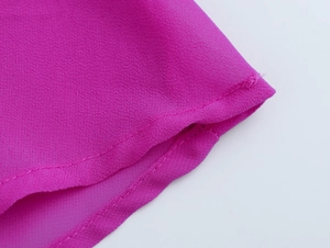 Primo piano delle cuciture professionali e dell'orlo pieghettato di questo abito in chiffon rosa