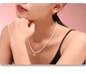 Détail d'un collier avec pendentif doré vintage et perles d'eau douce sur un modèle