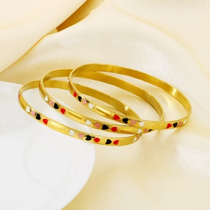 Three-piece stackable 18K gold-plated bangles with colorful enamel heart charms on satin