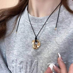 Close-up of golden hollow double heart pendant necklace worn on neck with black rope chain