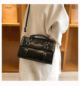 Detail of vintage black leather satchel showing silver studs and buckle strap accents