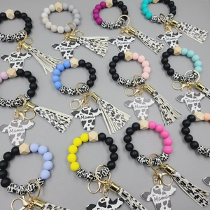 Detail of colorful Mama cow head silicone keychains with tassels and wooden beads