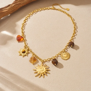 Vintage gold-plated sun and heart pendant necklace with amber beads on beige background