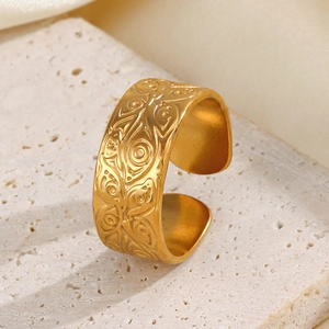 Vintage golden stainless steel open ring with etched eye pattern on stone background