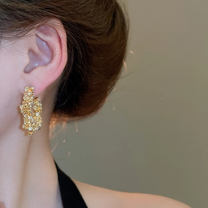 Close-up of elegant gold textured hoop earrings with sparkling crystal pavé on model
