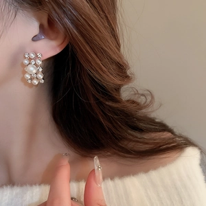 Detailed close-up of vintage gold earrings with pearls and rhinestones on a model