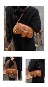 Close-up of brown vintage punk shoulder bag with silver metal rivets and buckle detail