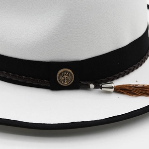Detail of white fedora hat with black ribbon, golden anchor button and brown tassel
