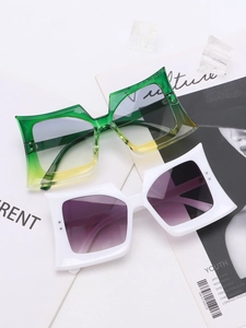 Detail view of large geometric sunglasses with green gradient lenses on a fashion magazine