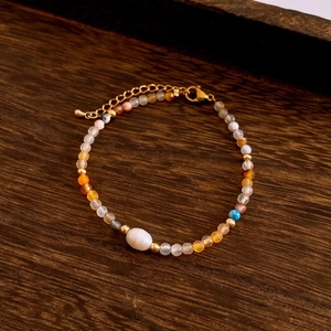 Detailed view of the beaded necklace featuring an adjustable lobster clasp on wood
