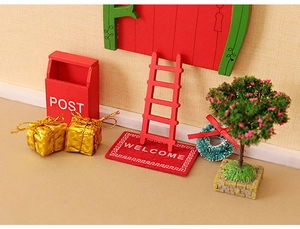 Close-up of a miniature Christmas dollhouse set with red wooden door and tiny post box