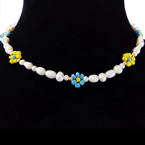 Detail of baroque pearl necklace with blue and yellow floral beads on black bust