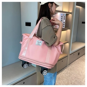Pink oxford expandable travel bag with 360 wheels and shoulder strap shown on model