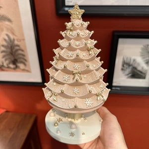 Pink Christmas tree music box with gold stars and bows on a white base for holiday decor