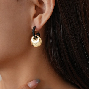 Detail showing a model wearing geometric gold metal and black ring drop earrings