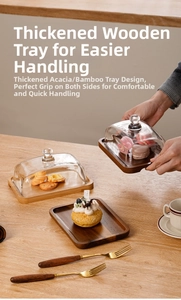 Detail of acacia wood butter dish with hand lifting a transparent glass lid in warm lighting