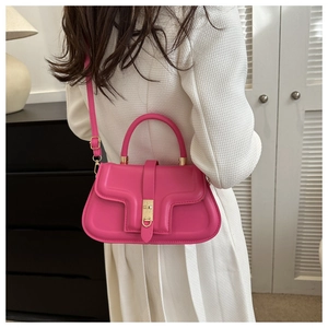 Close-up of vibrant rose pink leather shoulder bag with elegant gold buckle hardware