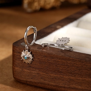 Macro shot of S925 sterling silver evil eye earrings with blue stones on a wooden box