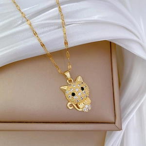 Close-up of a gold cat pendant with pavé cubic zirconia and a bow detail on a flat chain