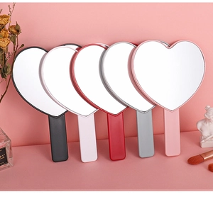 Detailed view of heart-shaped handheld mirrors in multiple colors with plastic handles