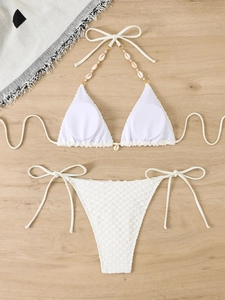 Detailed view of white waffle textured bikini featuring shell charms and lace-up straps