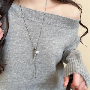 Detailed view of silver snake chain necklace with pearl and metal bead pendant on model