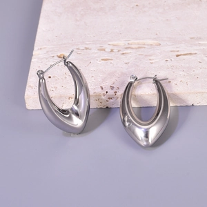 Detailed view of polished silver hollow C-shaped earrings on light textured stone
